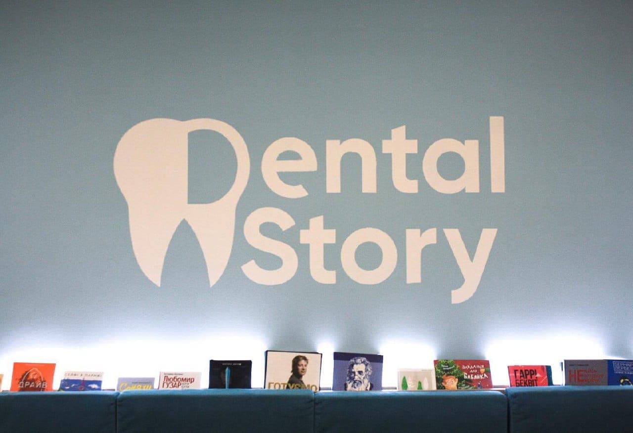 Зона очікування Dental Story — логотип на стіні та полиця з книжками